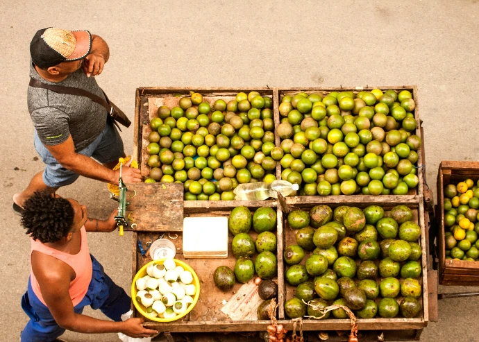 A man and a woman standing next to a cart of limes